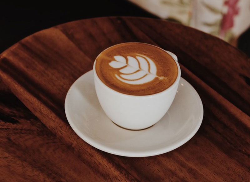 a cup of mocha latte on a saucer on a wooden table