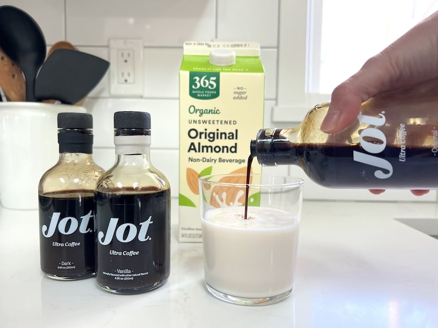Pouring Jot Original coffee into almond milk