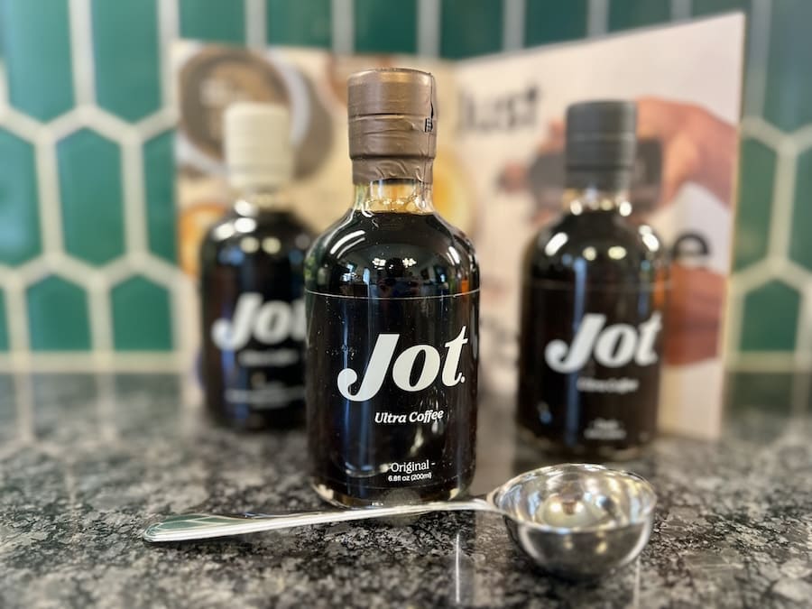 Three Jot coffee flavors in bottles with measuring spoon and recipe book